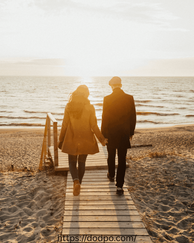 A couple taking a walk to the beach, holding hands together.