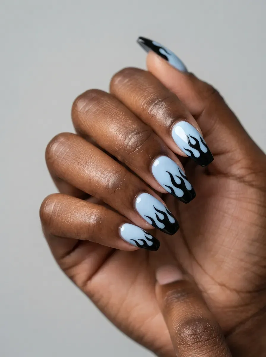 Baby blue nails with sharp black flame French tips on deep chestnut skin