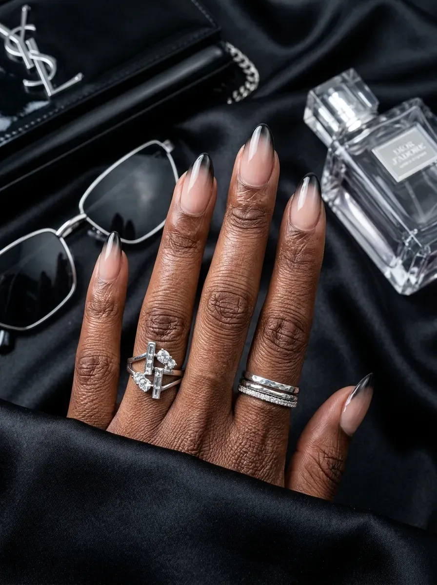 Black ombré French tips fading into nude almond nails on dark skin