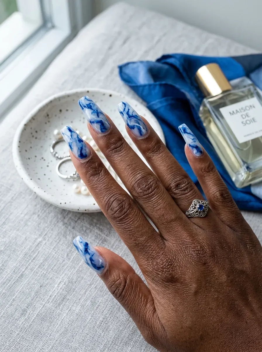 Long coffin nails with blue and white marble art on chestnut skin