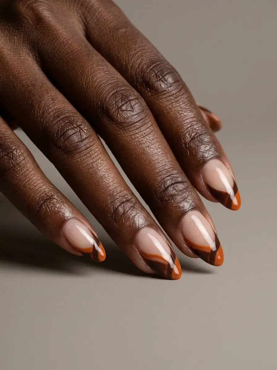 Medium almond nails with brown and burnt orange abstract French tip shapes
