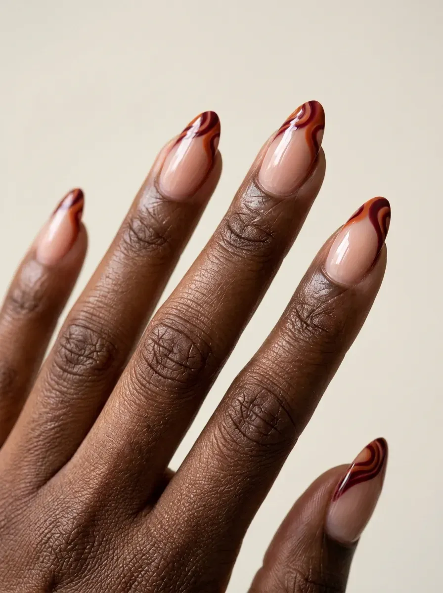 Almond nails with burnt orange and burgundy curved French swirl tips
