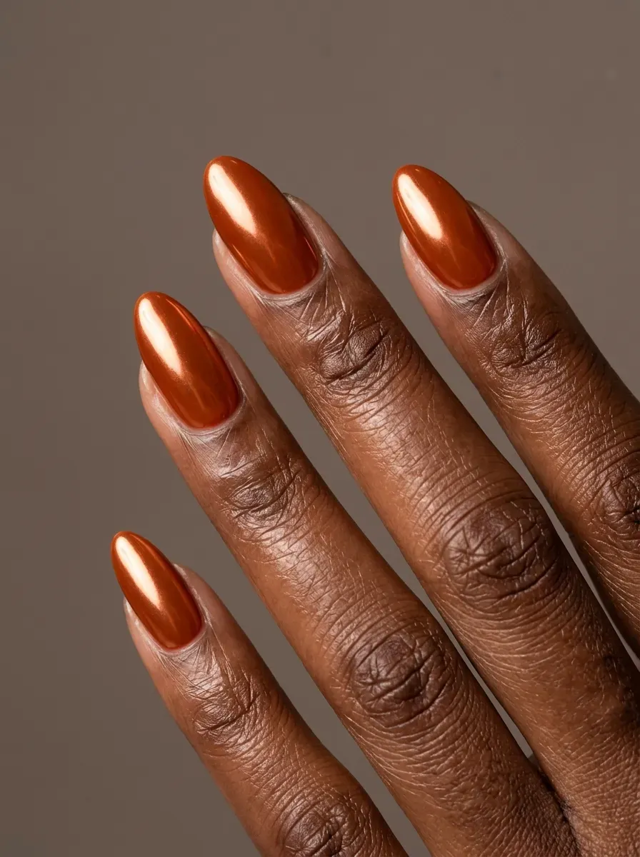 Burnt orange chrome almond nails with reflective autumn finish on deep brown skin