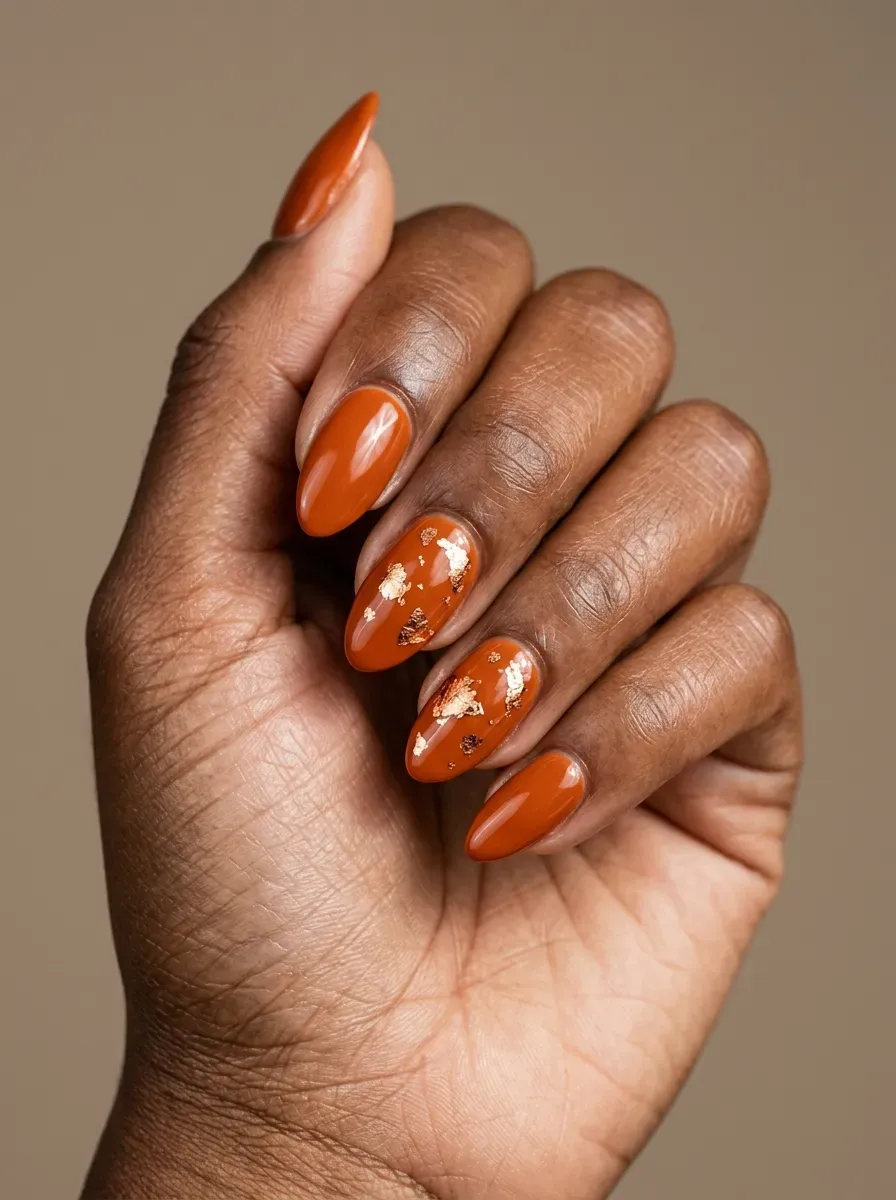Burnt orange nails with delicate copper foil fragments and glossy finish