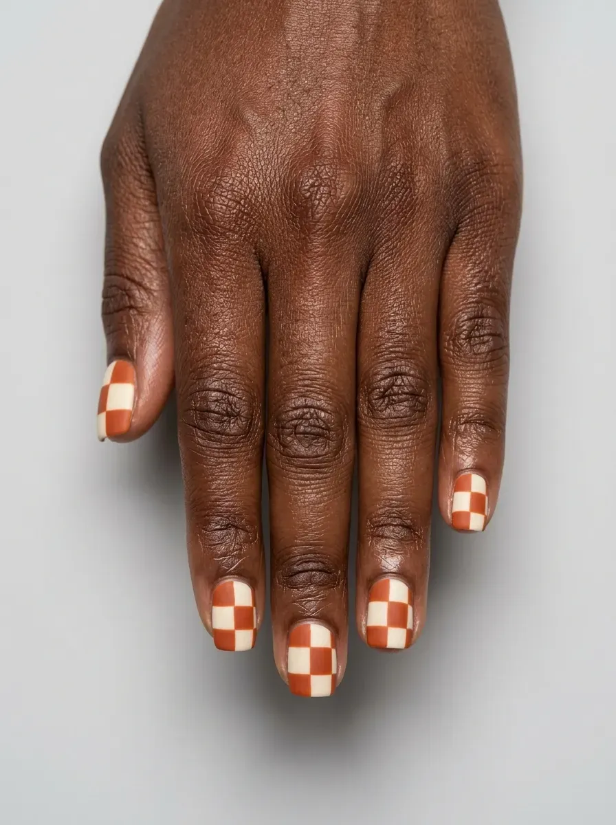 Burnt orange and cream checkerboard pattern on short square nails