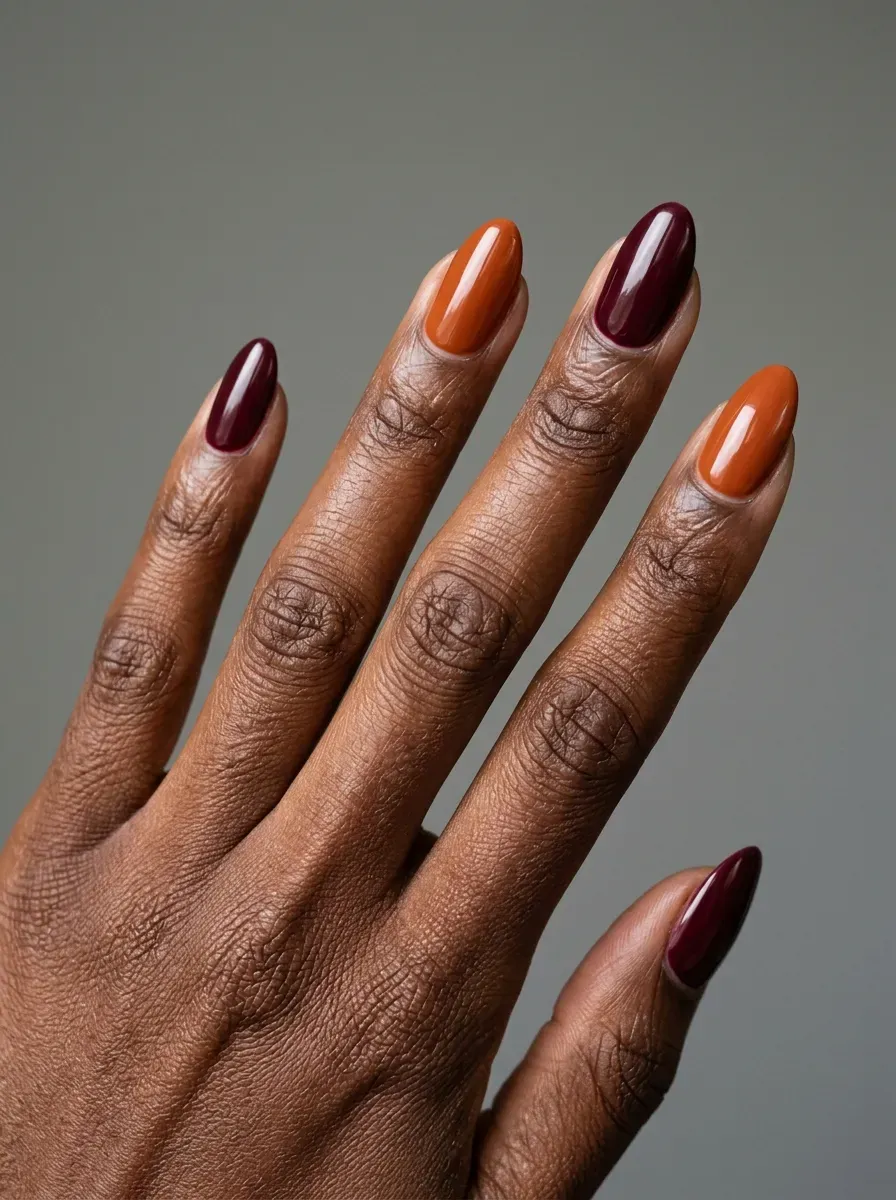 Burnt orange and deep burgundy alternating manicure on medium almond nails