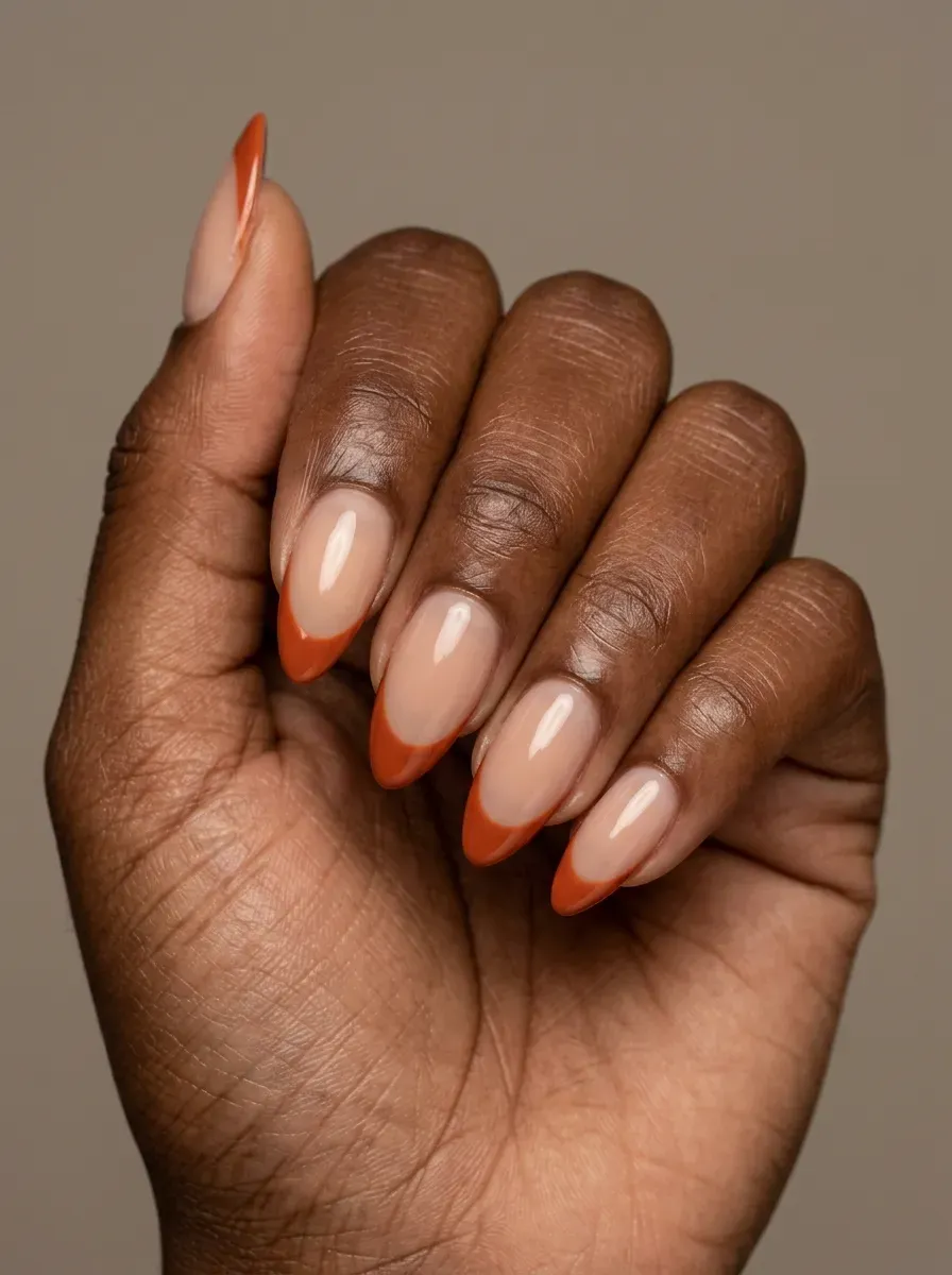 Almond nails with crisp burnt orange French tips on deep brown skin