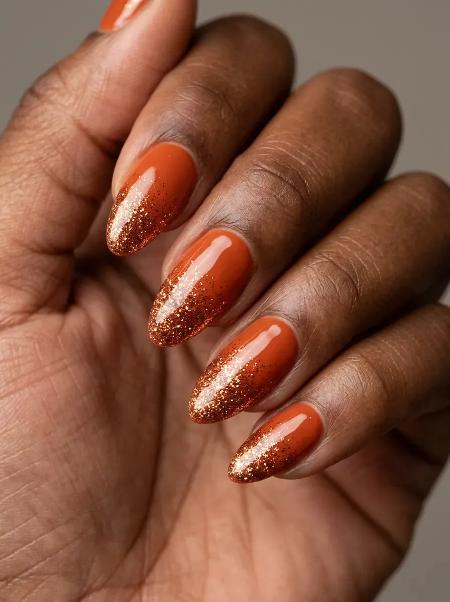 Burnt orange nails fading into fine copper glitter near the tips