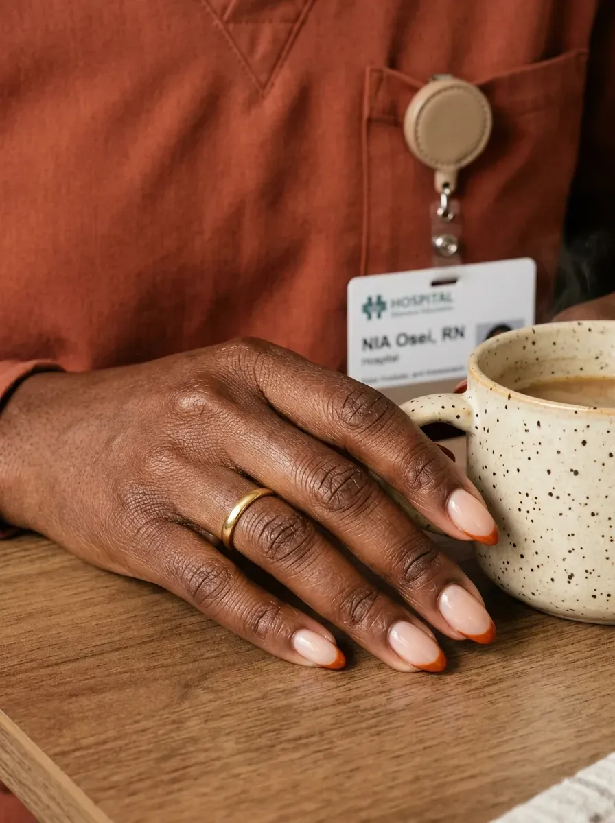 Short almond nails with burnt orange micro French tips on deep brown skin