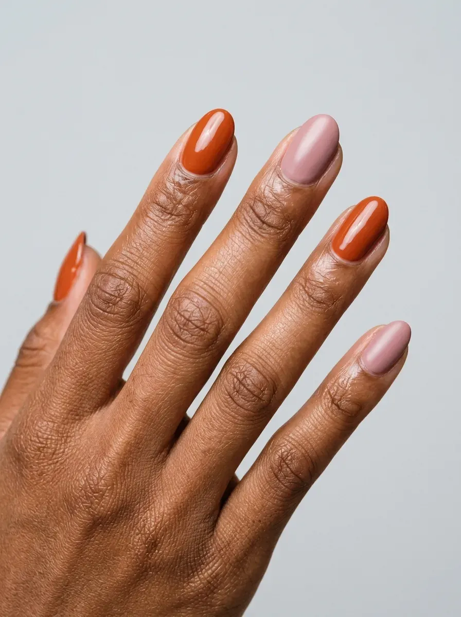 Burnt orange and muted soft pink alternating manicure on oval nails