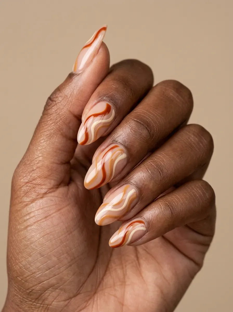 Burnt orange and cream swirl nail art across medium almond nails