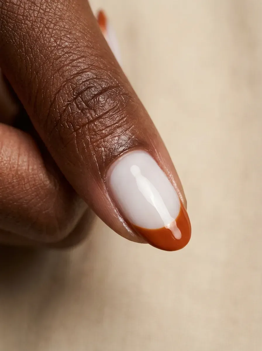 Burnt orange French tip over a soft milky white nail base