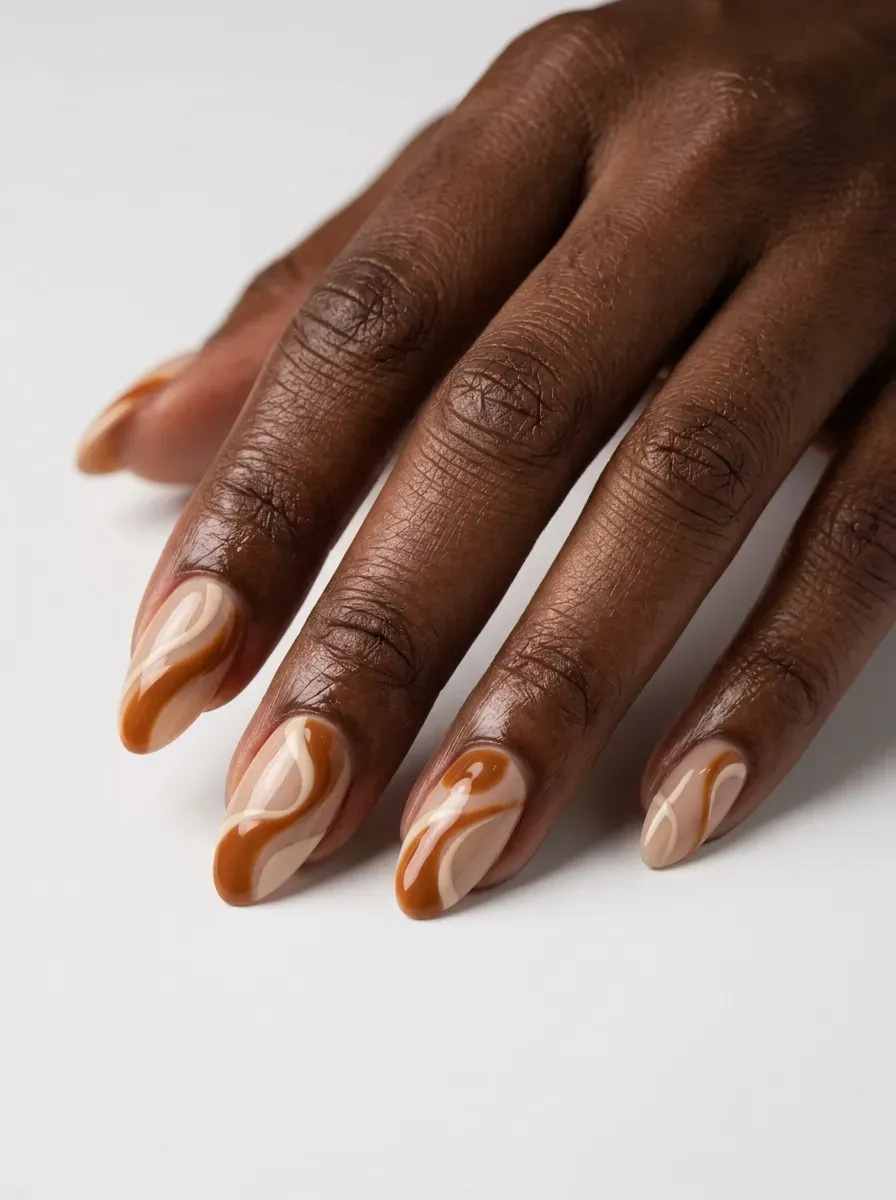 Medium almond nails with caramel and cream abstract gel shapes on dark skin