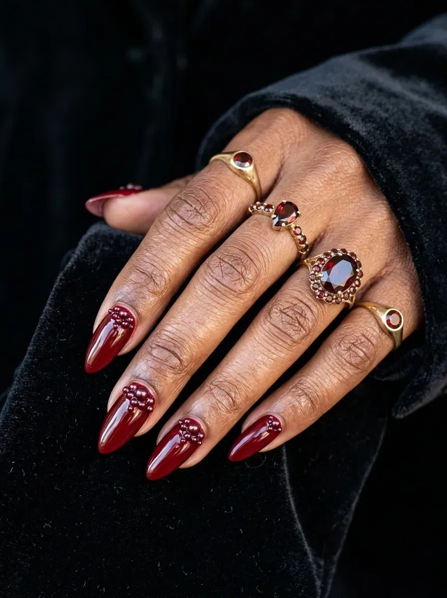 Glossy blood red nails accented with small dark red pearl clusters