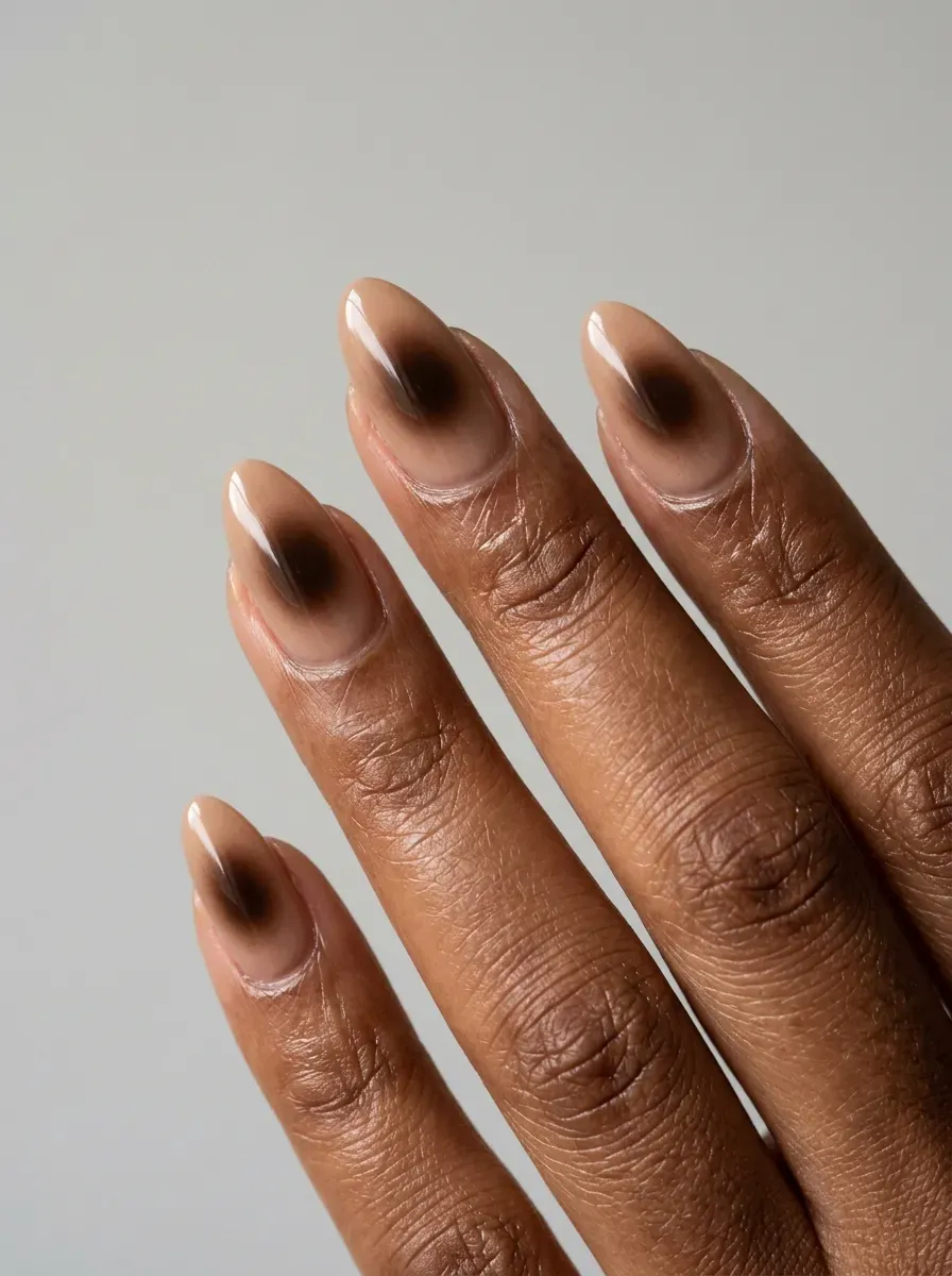 Medium almond nails with soft dark brown aura centers over neutral gel bases