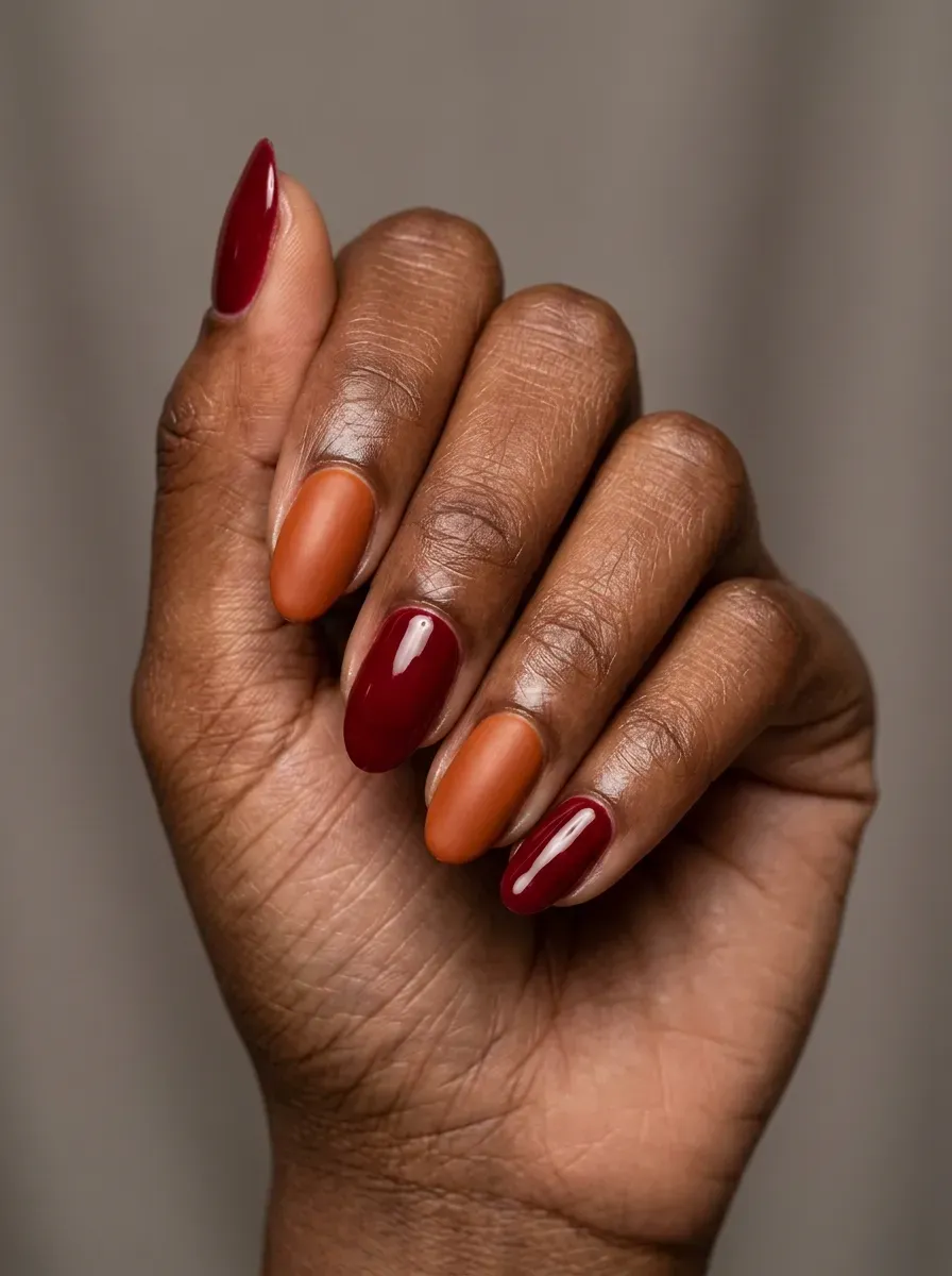 Glossy deep red gel nails with burnt orange accent nails on chestnut skin