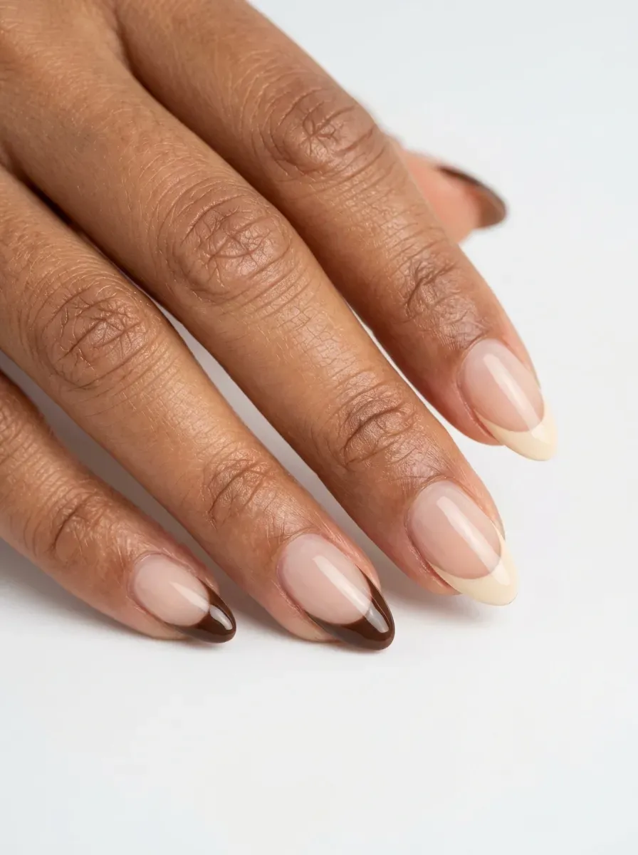 Short almond nails with espresso brown and cream French tips on warm skin