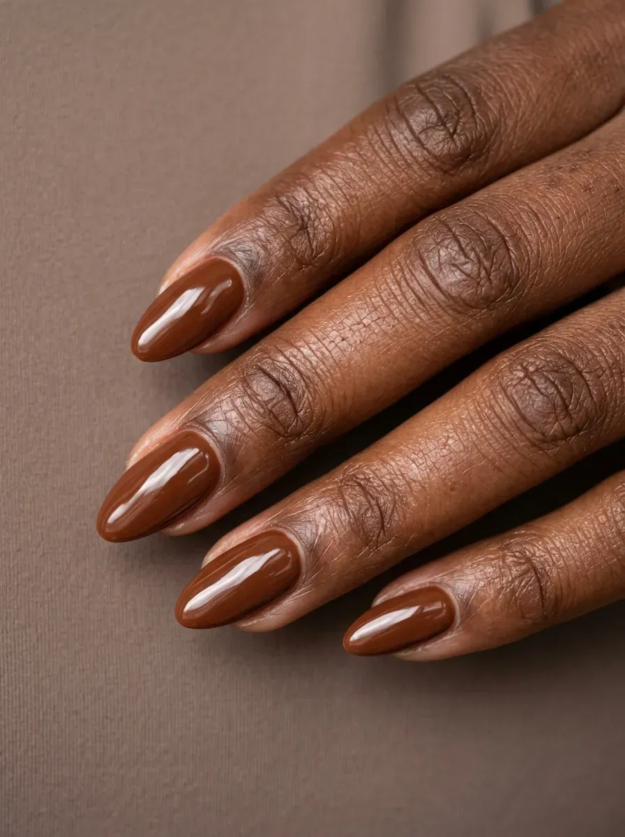 Medium almond nails with glossy chestnut brown gel polish on deep chestnut skin