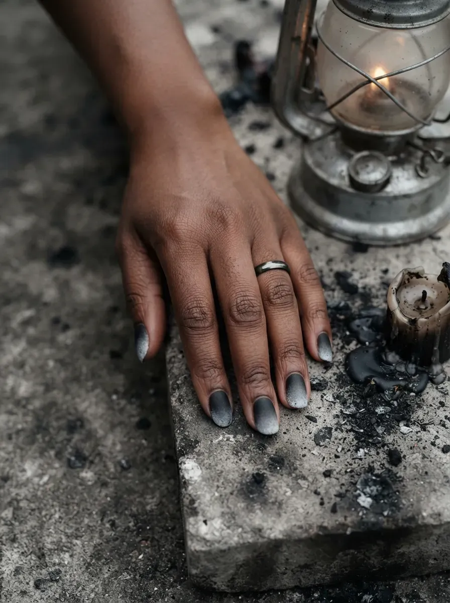 Close-up of matte black-to-grey rot ombre nail gradient on deep brown skin