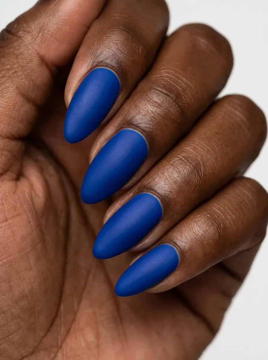Matte cobalt blue almond nails shown in close-up on a hand