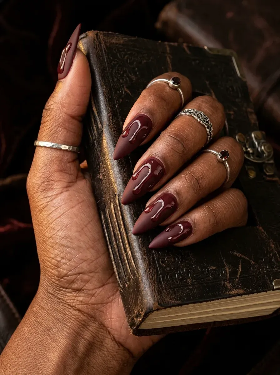 Deep oxblood red matte nails featuring raised glossy clear drips