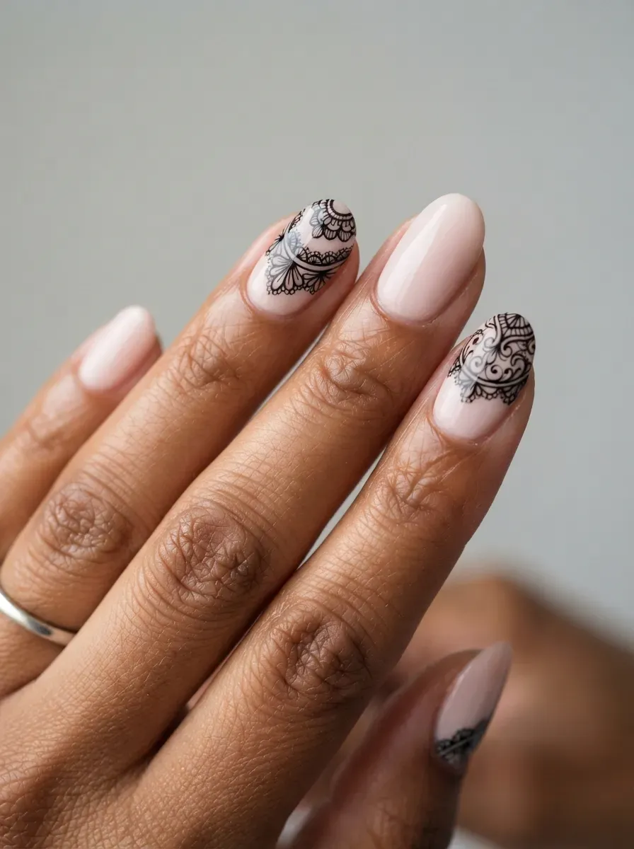 Pastel pink nails with delicate black lace-inspired line art on warm brown skin