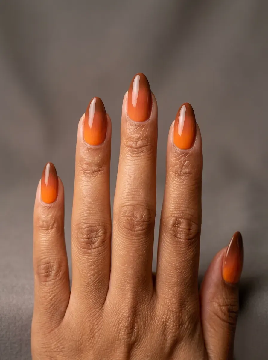 Almond nails blending pumpkin orange and warm brown gel shades on brown skin