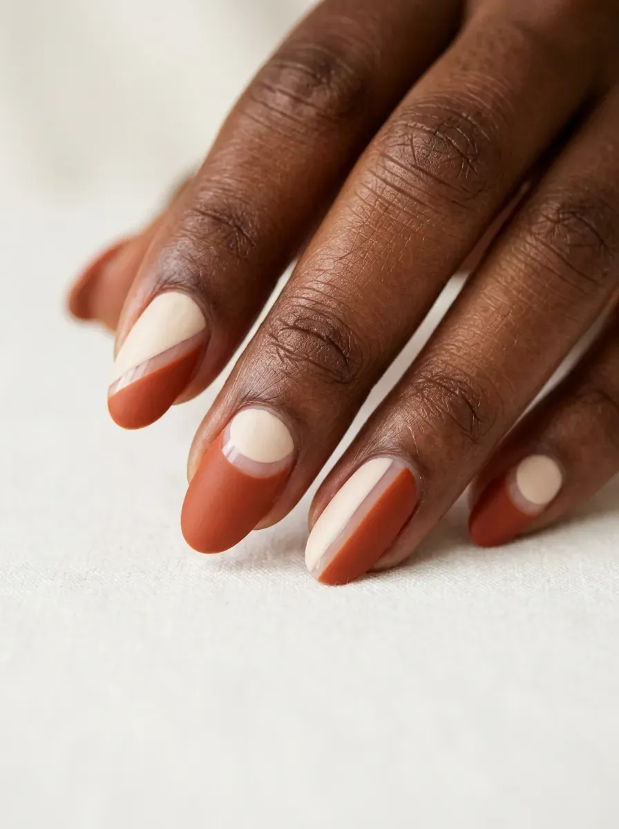 Medium oval nails with rust orange shapes and cream negative space
