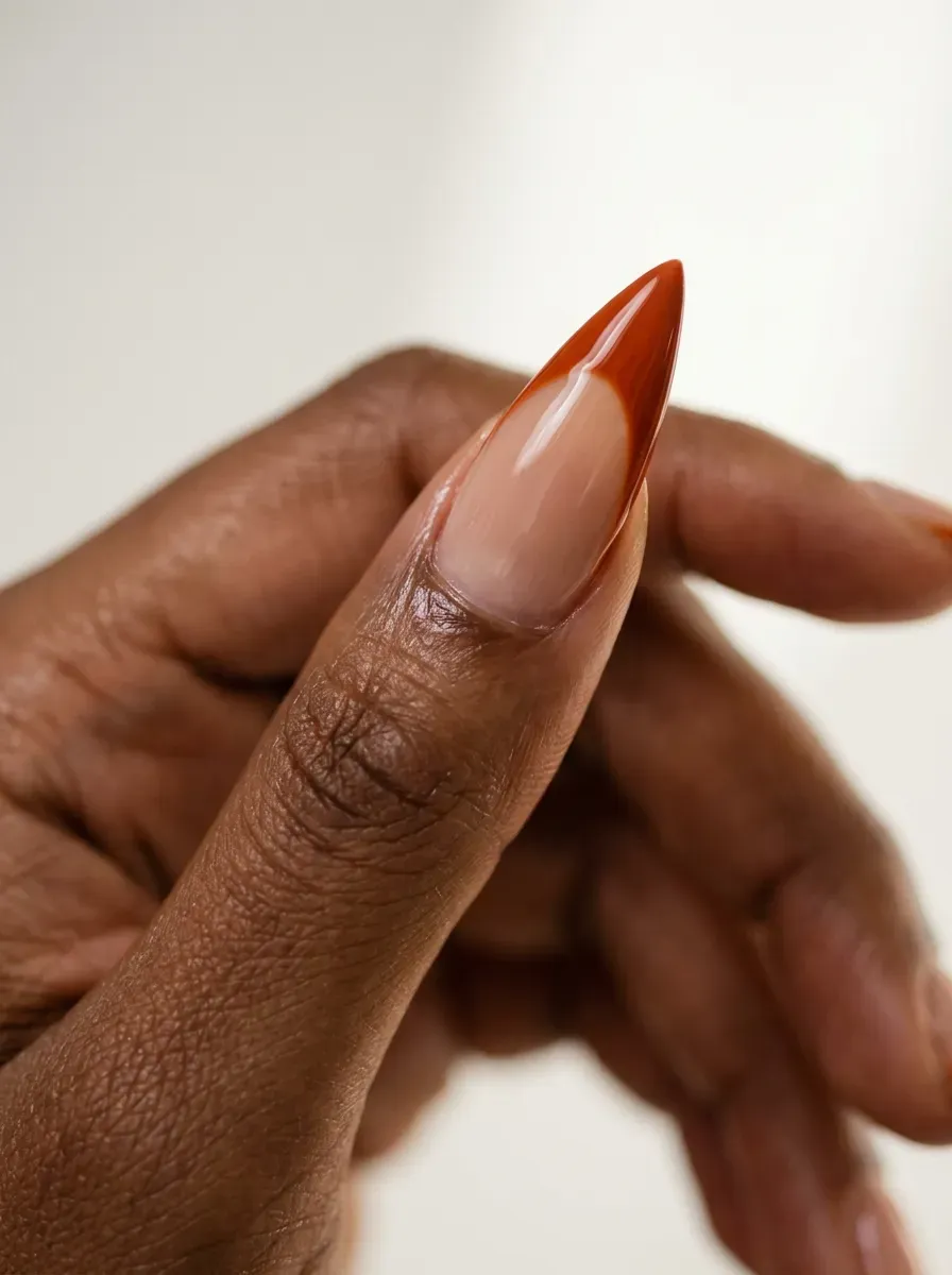 Long stiletto-shaped nails with a dramatic burnt orange French tip