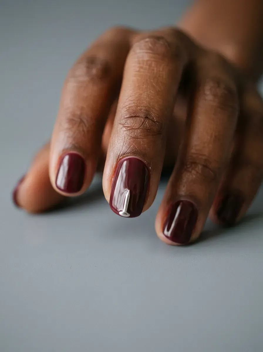 Small silver pin-shaped charm placed on an accent nail