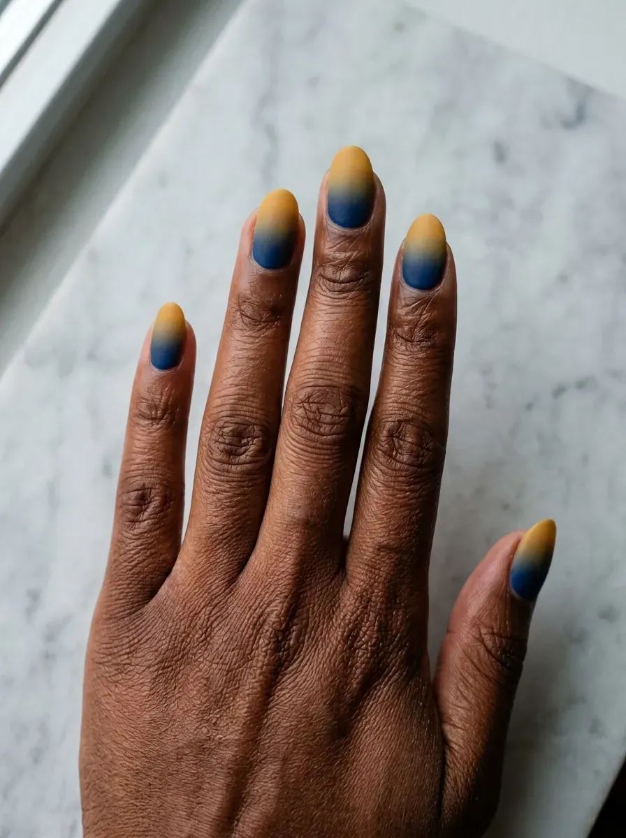 Ombre nails fading from mustard yellow to deep navy at the tip