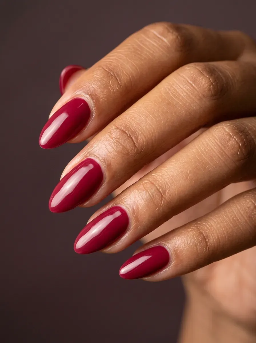 Cranberry red almond nails with glossy finish on warm brown skin