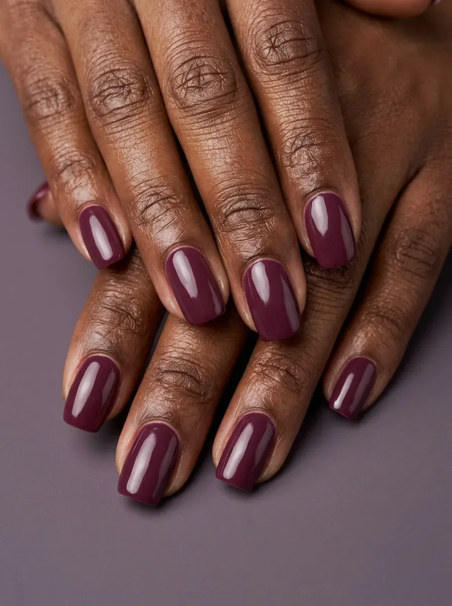 Deep mulberry gel nails with glossy finish on rich dark skin