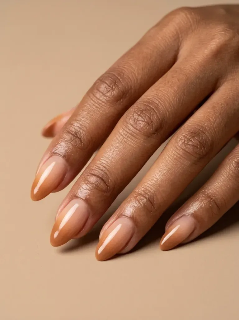 Muted caramel French ombre nails with soft nude gradient on warm skin