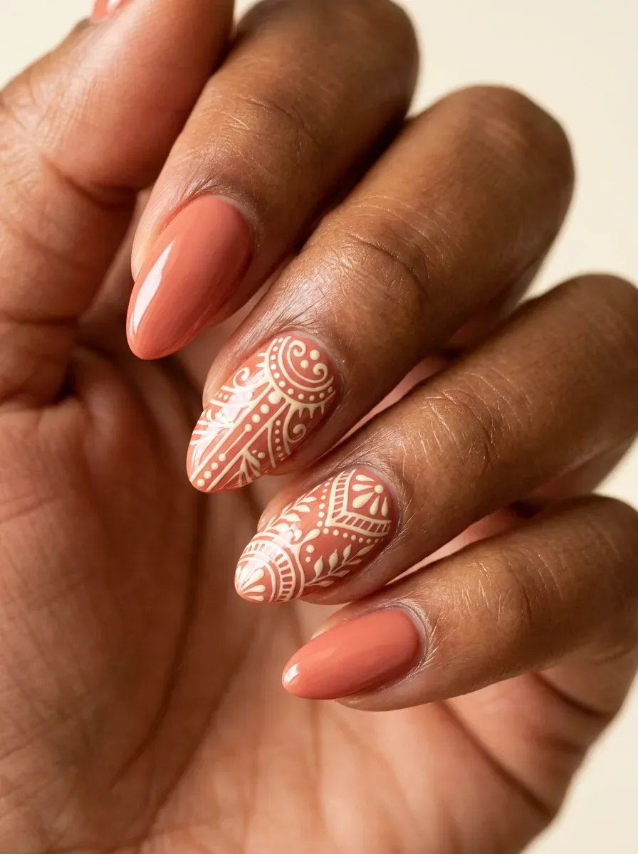 Short almond gel nails with muted coral polish and cream accent details