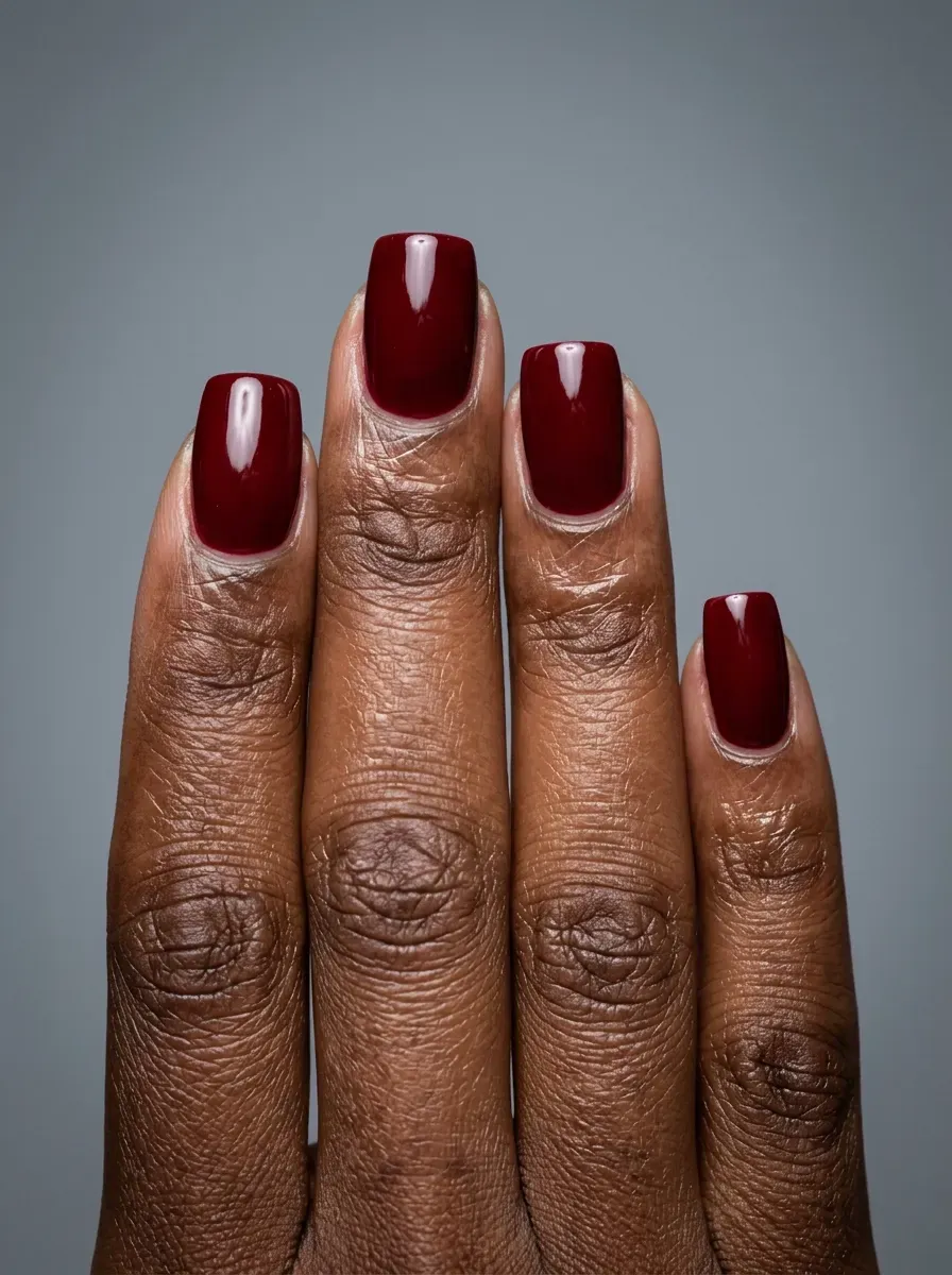 Deep oxblood gel nails with glossy finish on rich dark skin