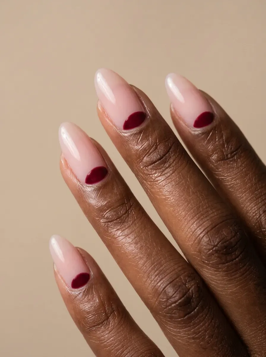 Medium almond gel nails with pink bases and burgundy reverse French curves