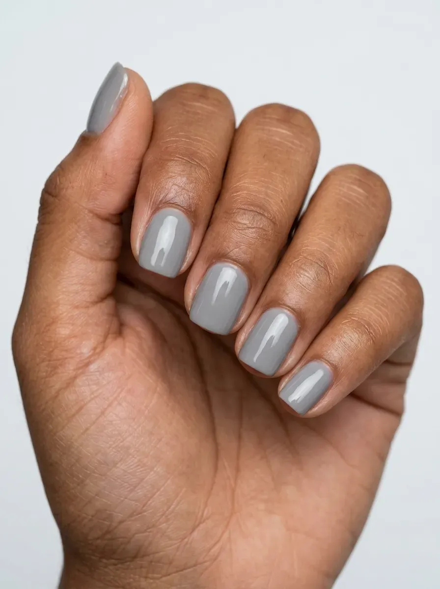 Short squoval gel nails painted soft gray with glossy reflective finish