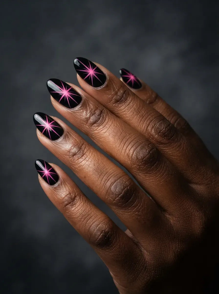 Close-up of black almond nails with pink starburst designs