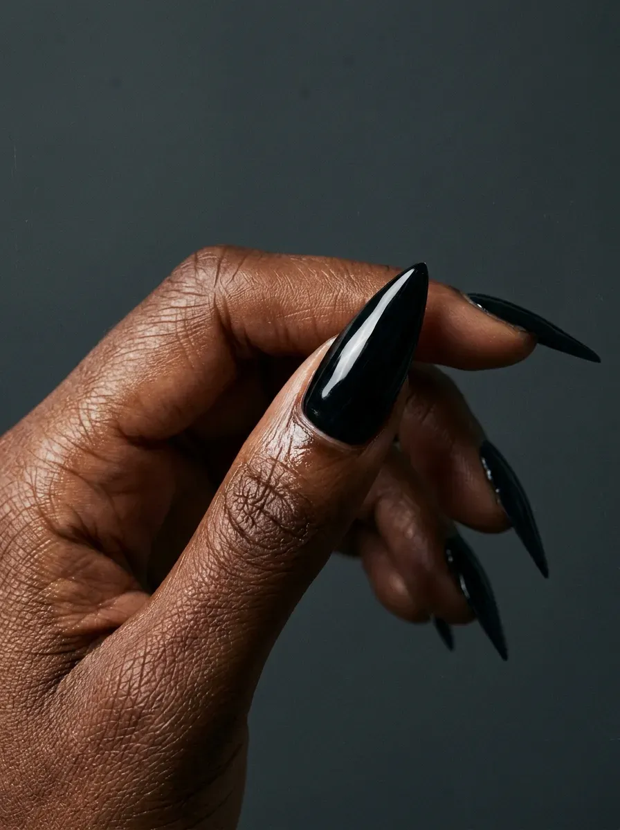 Glossy black manicure with vivid red eye accents on deep chestnut skin