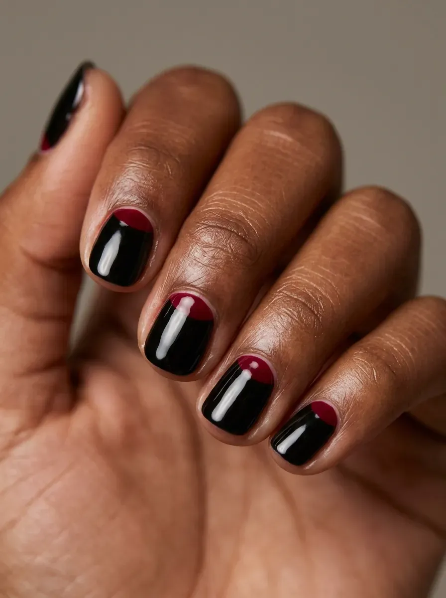 Black nails with deep red half-moon accents near the cuticles