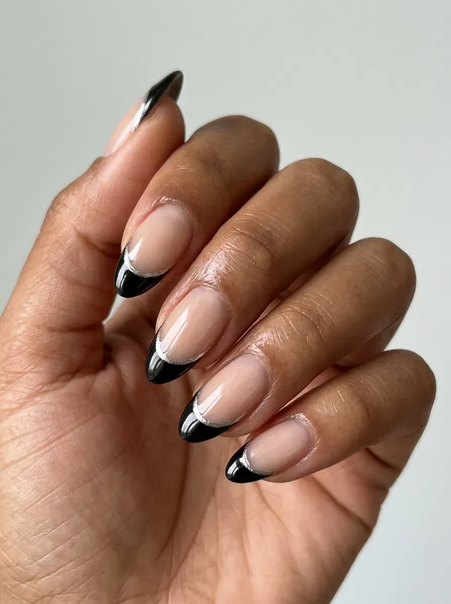 Black French tips with thin silver outlines on sheer nude almond nails