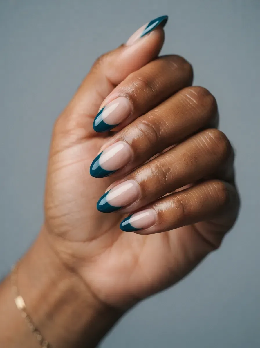 Medium almond nails with glossy deep teal French tips and neutral bases