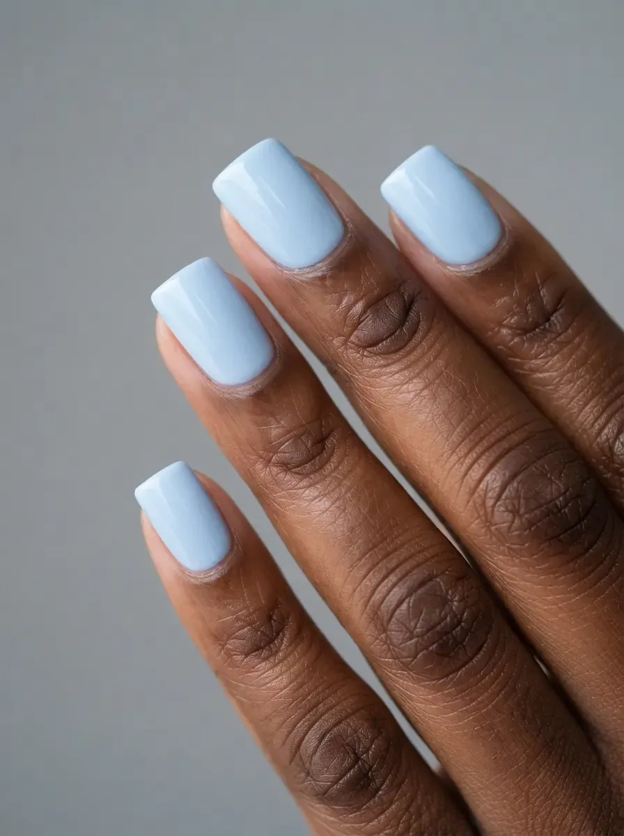 Close-up of short almond nails in dusty periwinkle creme on deep brown skin