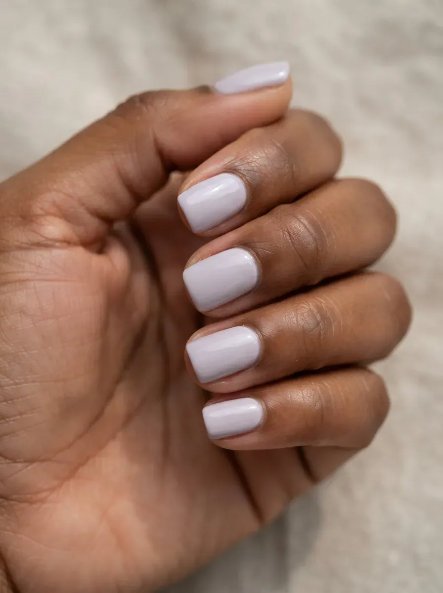 Close-up of short squoval nails in pale lilac creme on warm brown skin