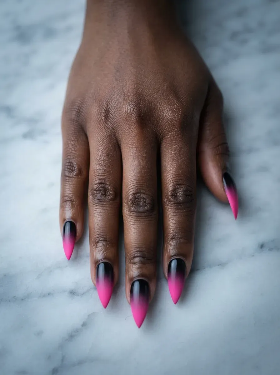 Close-up of stiletto nails fading from hot pink to black ombre