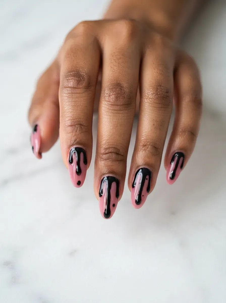 Close-up of glossy black nails with pink slime drips