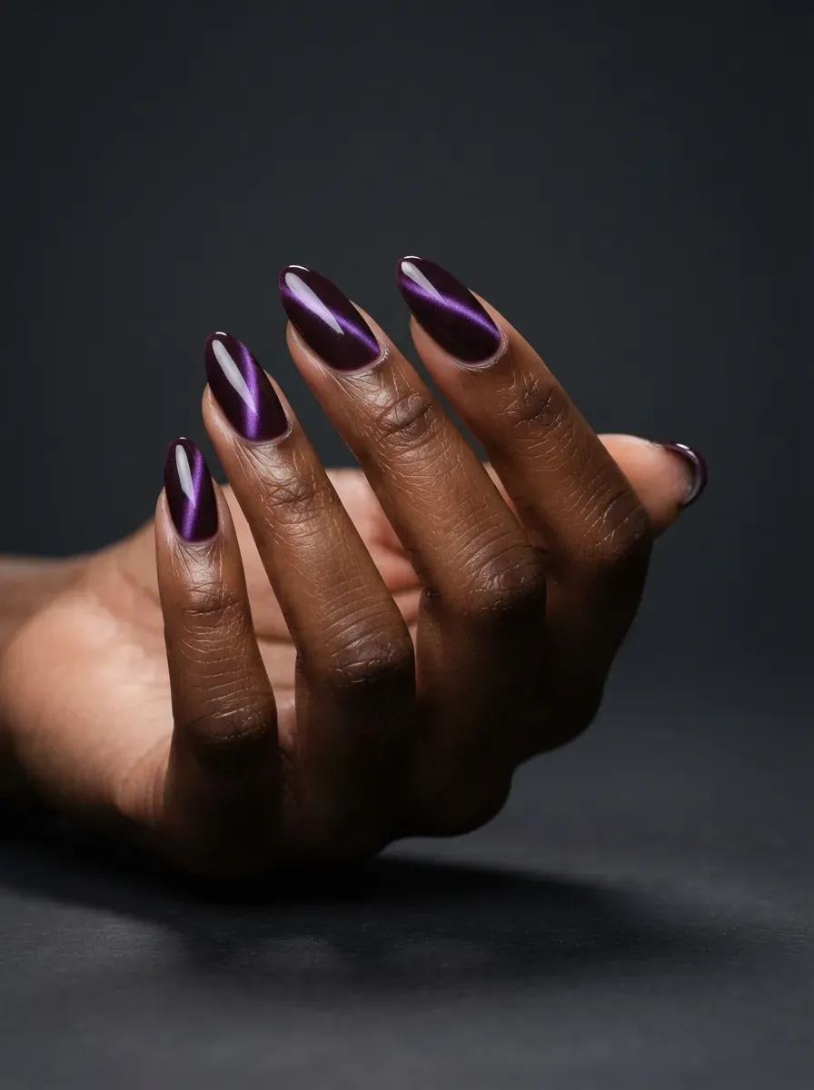Deep plum almond nails with luminous purple magnetic cat-eye shimmer