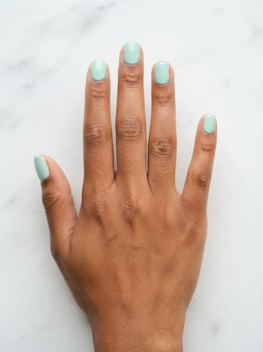 Close-up of short square nails in powder blue creme polish on deep chestnut skin