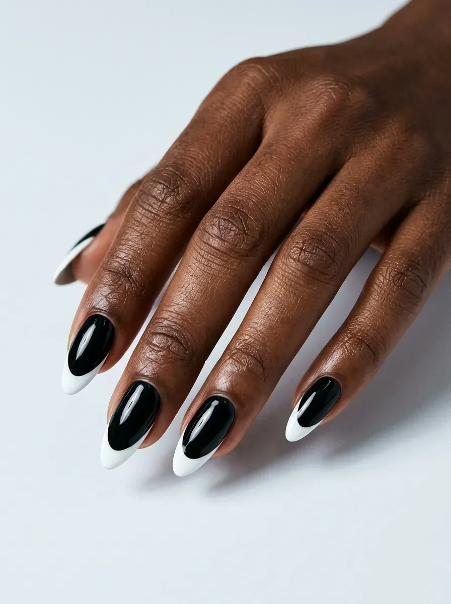 Glossy black nails with crisp white French tips and eerie contrast